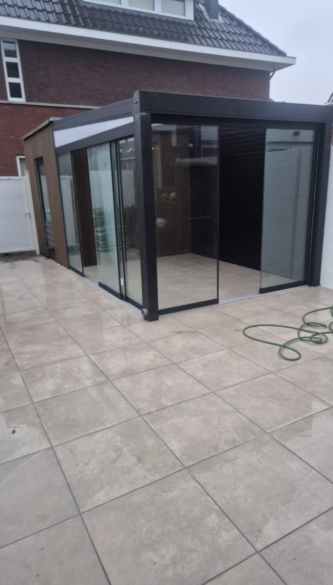 Veranda met glazen schuifwanden op tegelterras
